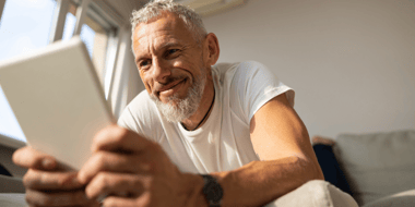 man smiling while looking at tablet