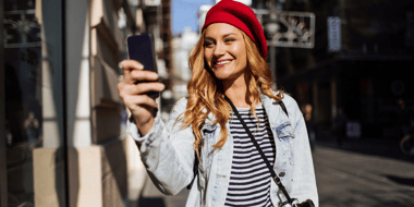 smiling woman on the street looking at her cellphone