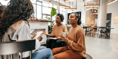 three women having coffee and working